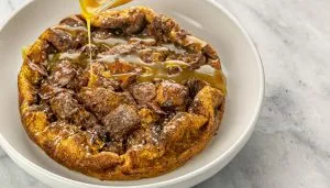 Bread pudding with praline sauce being drizzled over the top