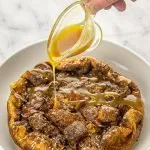 Bread pudding with a hand pouring praline sauce over the top