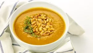 bowl of butternut squash soup with pine nuts and fresh thyme sprigs