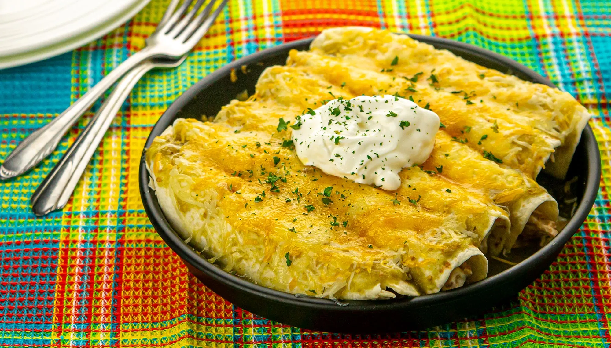 cheese covered pork enchiladas topped with sour cream