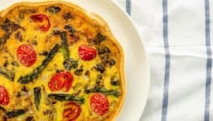 Top view of a quiche with tomatoes and asparagus
