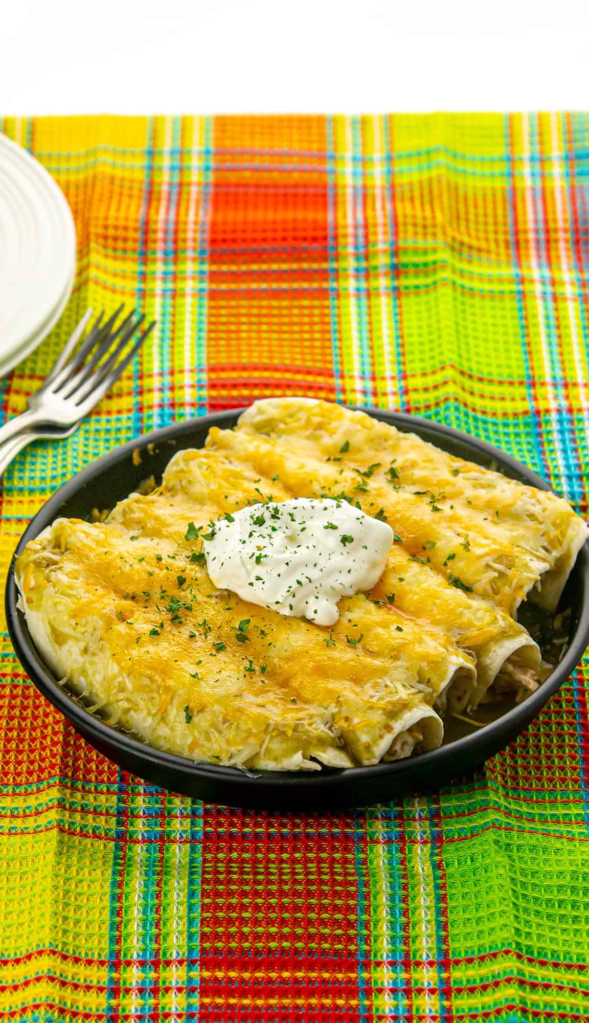 cheese covered pork enchiladas topped with sour cream