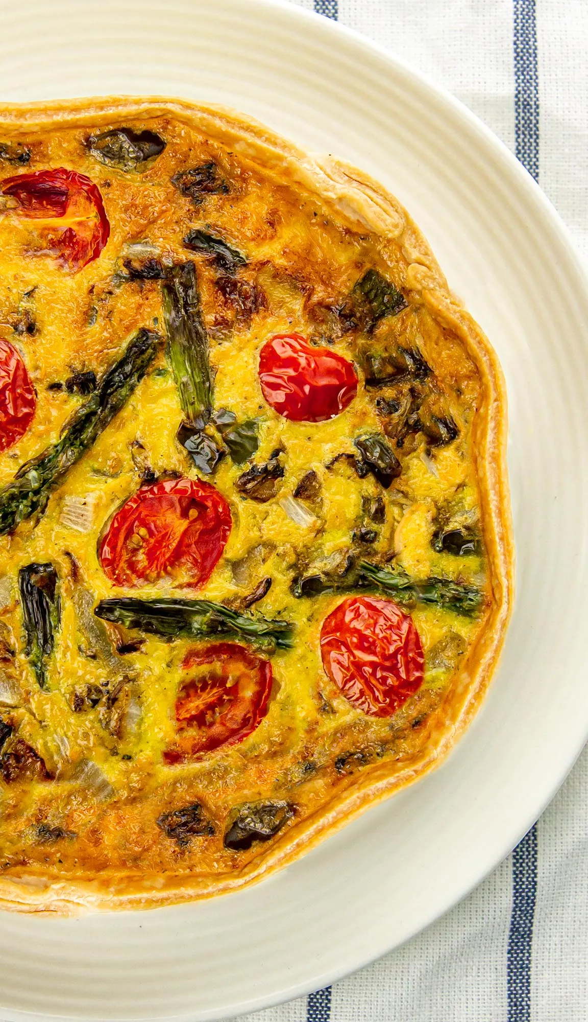Top view of a quiche with tomatoes and asparagus