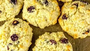 Close-up of baked scones with dried cherries on brown parchment paper.