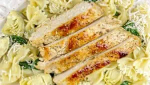 Grilled chicken breast strips on bowtie pasta with spinach, artichoke hearts, and shredded cheese.