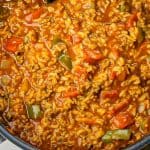 Pot of stuffed pepper soup with ground meat, rice, diced carrots, green bell peppers, and tomato-based sauce.