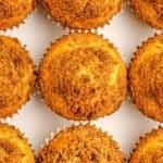 Nine golden brown crumb-topped muffins arranged in three rows on a white background.