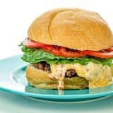 Cheeseburger with lettuce and tomato on a blue plate, cheese melting over the beef patty.